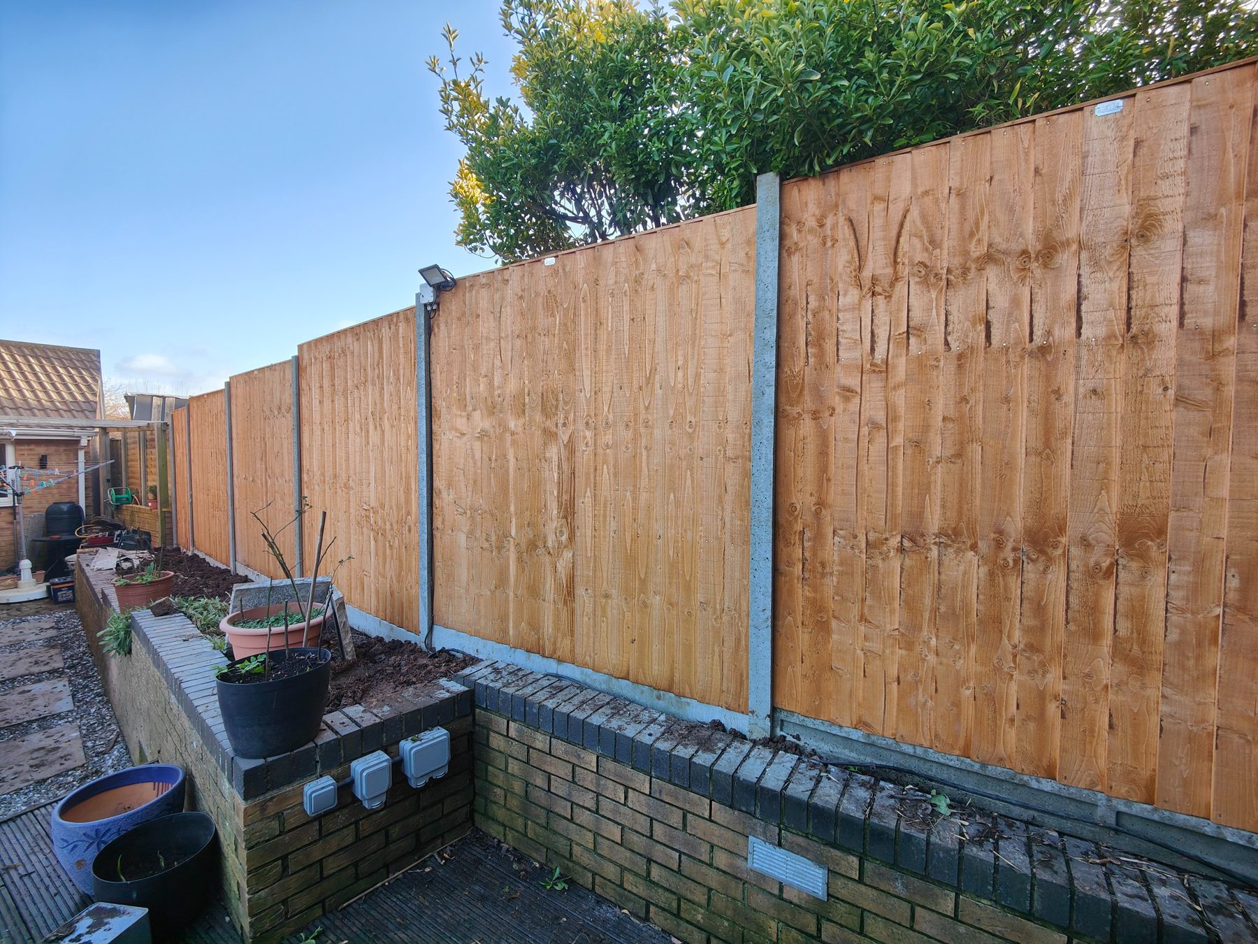 Long run of closeboard fence on retaining wall